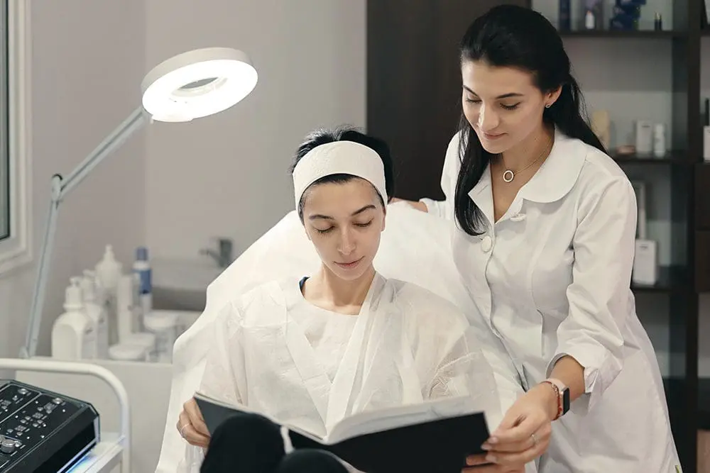Aesthetics School Teacher Revising Lecture Coursework With Student For Medical Aesthetician Licensing Diploma At FAMA - Aesthetic Nurse Florida Requirements