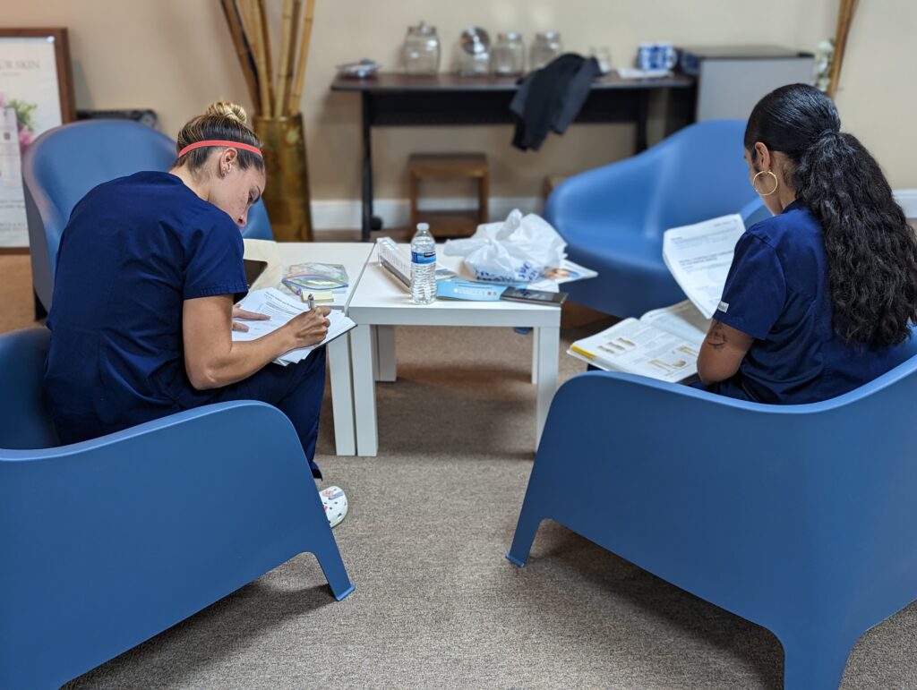 Medical esthetician students reviewing notes for business class on how to manage social media