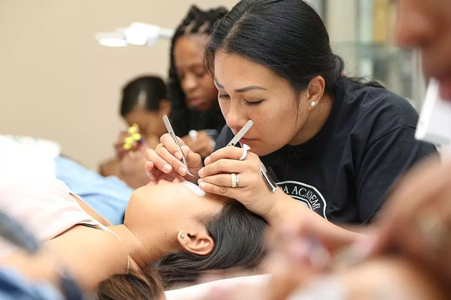 FAMA student applying eyelash extensions to a model in the training clinic