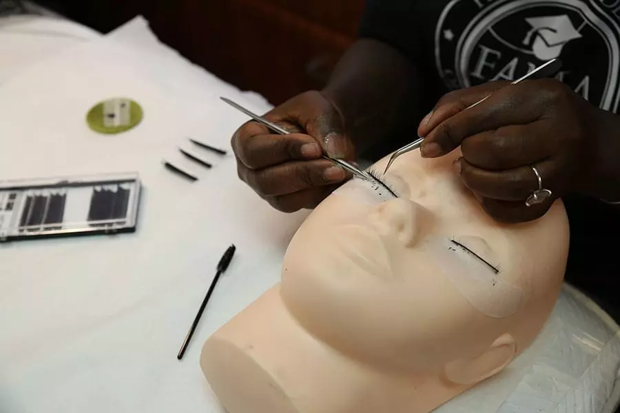 FAMA student practicing eyelash extension application on a training mannequin head