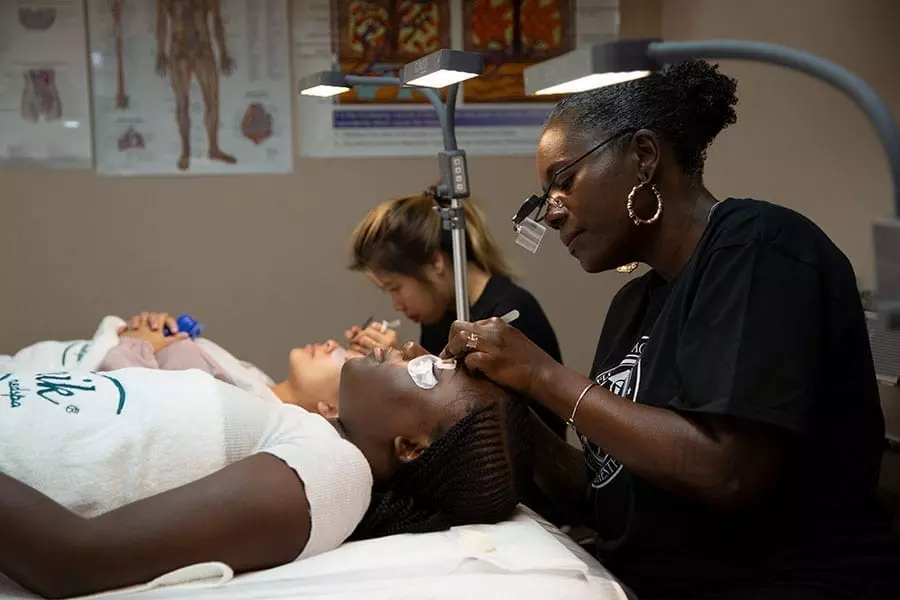 FAMA students practicing eyelash extension application on models in the training clinic