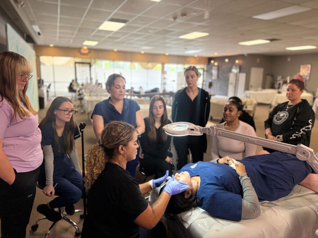 FAMA instructor demonstrating a facial treatment technique to a group of students in the training clinic